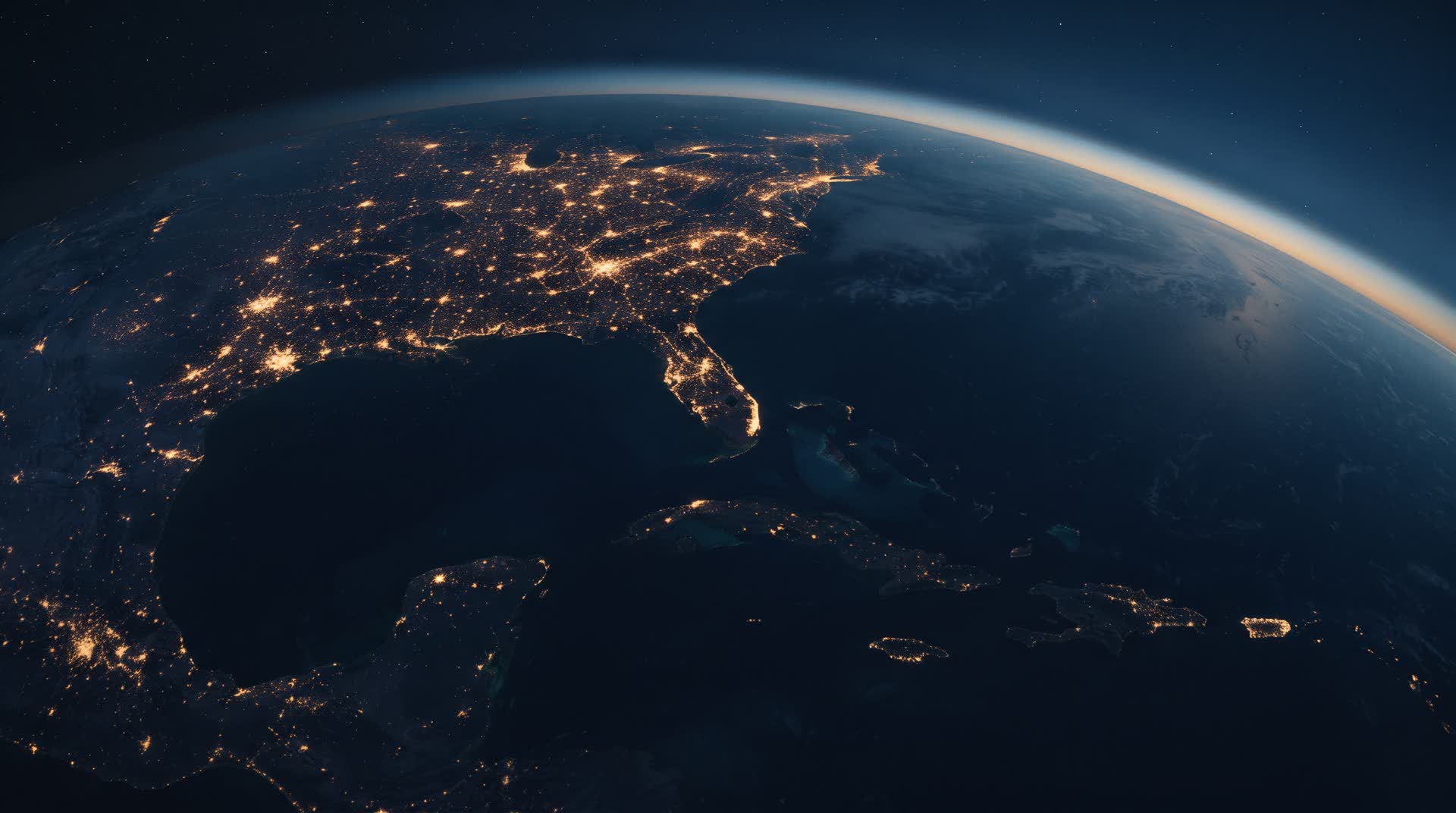 The Gulf-Caribbean arc from orbit before dawn, coastal cities burning as points of light.